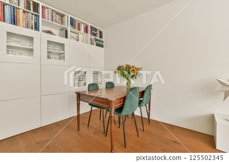 A stylish dining room showcasing a wooden table surrounded by green chairs, complemented by a floral centerpiece, creating an inviting modern atmosphere. A stylish dining room showcasing a wooden table surrounded by green chairs, complemented by a floral centerpiece, creating an inviting modern atmosphere. 125502345