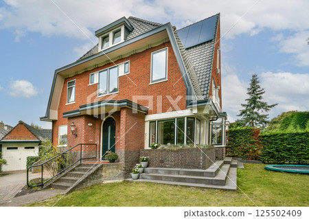 A contemporary brick house featuring large windows, a neatly landscaped lawn, and a minimalist design. Includes outdoor stairs and a serene environment. 125502409