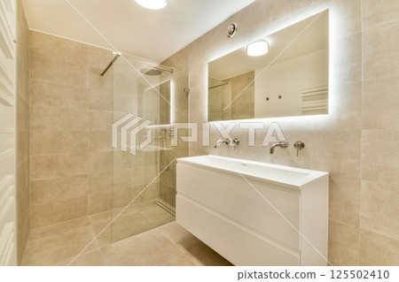 A stylish and contemporary bathroom featuring a glass shower, sleek vanity, and warm lighting, emphasizing minimalist design elements and functionality. A stylish and contemporary bathroom featuring a glass shower, sleek vanity, and warm lighting, emphasizing minimalist design elements and functionality. 125502410