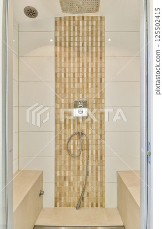 A sleek and contemporary shower room featuring tiled walls, a rainfall showerhead, and minimalist decor for a luxurious bathing experience. A sleek and contemporary shower room featuring tiled walls, a rainfall showerhead, and minimalist decor for a luxurious bathing experience. 125502415