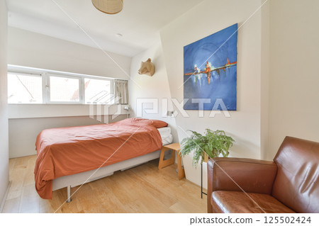 A contemporary bedroom featuring a cozy bed, elegant decor, and natural light filtering through the windows. Ideal for relaxation and comfort in a minimalist setting. A contemporary bedroom featuring a cozy bed, elegant decor, and natural light filtering through the windows. Ideal for relaxation and comfort in a minimalist setting. 125502424