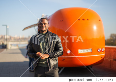 African american man posing in front of a colorful food truck. Concept of travel, style, leisure and confidence African american man posing in front of a colorful food truck. Concept of travel, style, leisure and confidence 125502464