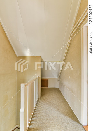 A spacious hallway featuring light-colored walls and a white railing, creating a welcoming atmosphere. The design emphasizes simplicity and openness. 125502482