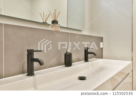 Sleek and stylish bathroom sink featuring modern black faucets, clean lines, and a minimalist aesthetic. Perfect for contemporary interior designs. 125502530