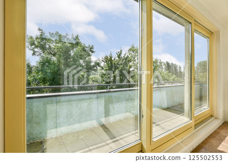 A bright and airy scene featuring a modern window with clear glass, showcasing lush greenery outside and a sunny sky, creating an inviting atmosphere. A bright and airy scene featuring a modern window with clear glass, showcasing lush greenery outside and a sunny sky, creating an inviting atmosphere. 125502553
