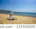Toddler playing with sand on the beach 125502609