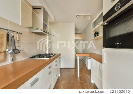 A sleek and modern kitchen featuring minimalist cabinetry, wooden countertops, and contemporary appliances that create an inviting cooking space. 125502620