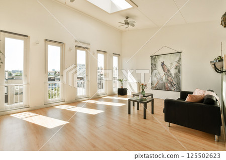 A spacious and luminous living room featuring large windows, minimalist furniture, and a peaceful atmosphere, ideal for relaxation and gatherings. A spacious and luminous living room featuring large windows, minimalist furniture, and a peaceful atmosphere, ideal for relaxation and gatherings. 125502623