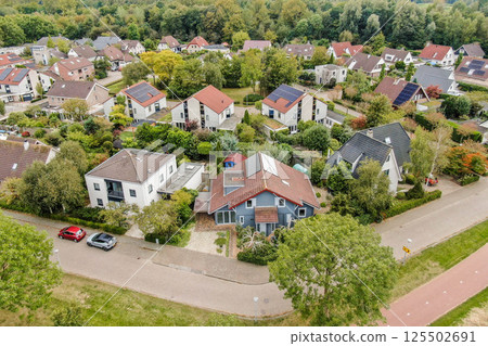 A picturesque aerial view showcases a vibrant residential neighborhood, highlighting diverse houses, lush greenery, and winding streets. A picturesque aerial view showcases a vibrant residential neighborhood, highlighting diverse houses, lush greenery, and winding streets. 125502691