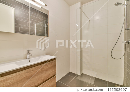 Sleek and contemporary bathroom featuring elegant fixtures, minimalist cabinetry, and bright tile design. A perfect blend of style and functionality in a modern space. 125502697