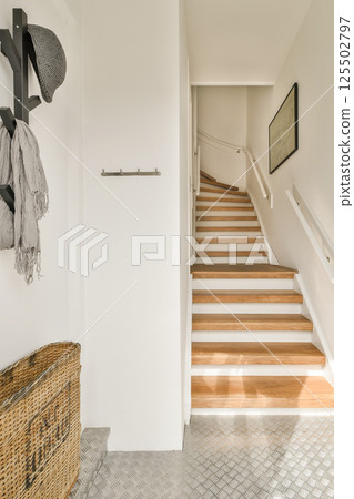 A bright, modern interior showcasing wooden stairs and a stylish entryway, highlighted by subtle textures and minimalistic decor. A bright, modern interior showcasing wooden stairs and a stylish entryway, highlighted by subtle textures and minimalistic decor. 125502797