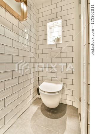 A stylish modern bathroom featuring sleek wall tiles, a contemporary toilet, and minimalistic design elements for an elegant look. 125502811