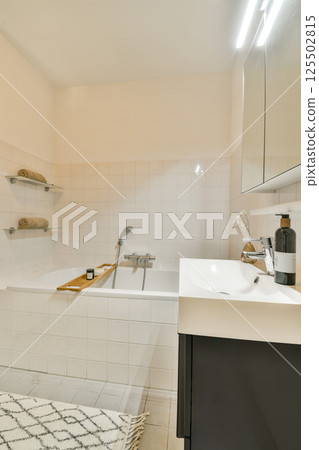 A stylish and contemporary bathroom featuring a sleek bathtub, modern sink, and minimalistic decor for a serene ambiance. A stylish and contemporary bathroom featuring a sleek bathtub, modern sink, and minimalistic decor for a serene ambiance. 125502815