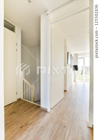 An elegant modern hallway featuring light wooden flooring, bright walls, and a minimalist aesthetic. The space is inviting with ample natural light. 125502836