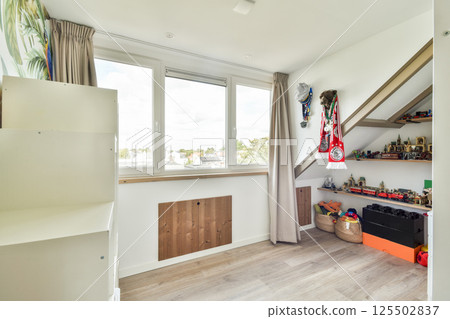 A well-designed interior featuring ample natural light, modern decor, and organized shelves with decorative items, creating a welcoming atmosphere. 125502837