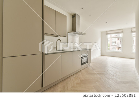 Sleek and contemporary kitchen design featuring light cabinetry, stainless steel appliances, and ample natural light from large windows. 125502881