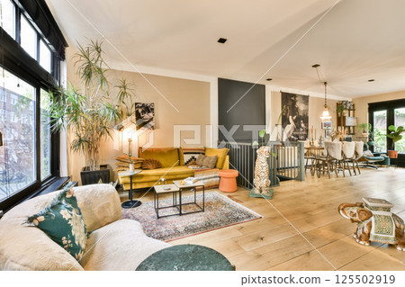 A beautifully designed living space featuring modern furniture, indoor plants, and a well-lit atmosphere that combines comfort with style. 125502919