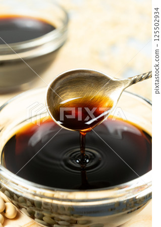 Soy sauce poured from a spoon into a saucepan close-up 125502934