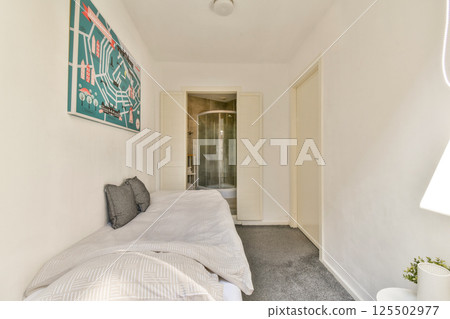 A serene and stylish interior shot showcasing a cozy living area with minimalistic decor and a glimpse of a bathroom in the background. 125502977