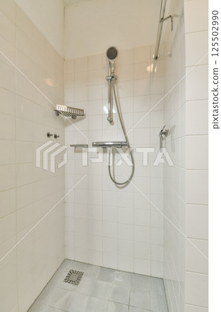 A contemporary shower stall featuring clean, white tiled walls and a sleek shower head. The design emphasizes simplicity and functionality. A contemporary shower stall featuring clean, white tiled walls and a sleek shower head. The design emphasizes simplicity and functionality. 125502990