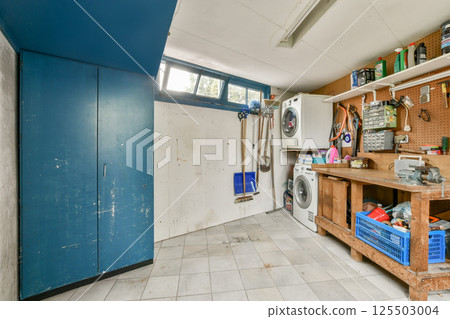 A functional and inviting laundry room featuring a combination of cabinets, a workbench, and modern appliances, enhancing efficiency in home chores. 125503004