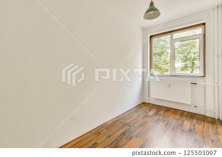 A sparse interior featuring a window that lets in natural light, highlighting the wood floor and clean walls. Ideal for modern design inspiration. 125503007