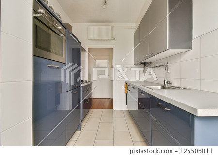 A sleek modern kitchen featuring blue cabinetry, minimalist design, and ample natural light, ideal for culinary creativity and gatherings. A sleek modern kitchen featuring blue cabinetry, minimalist design, and ample natural light, ideal for culinary creativity and gatherings. 125503011