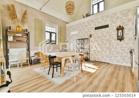 An inviting modern interior featuring wooden furniture, a cozy dining area, and natural elements like pampas grass, creating a warm atmosphere. 125503014