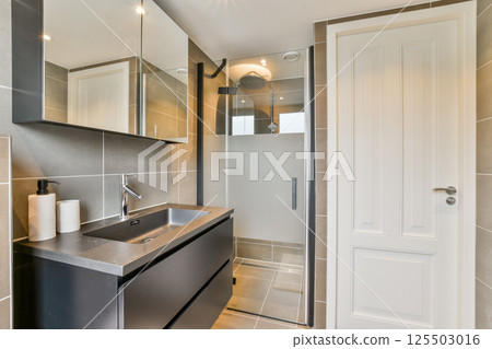 A contemporary bathroom featuring a walk-in shower, stylish sink, and elegant lighting, showcasing modern design elements and functionality. 125503016