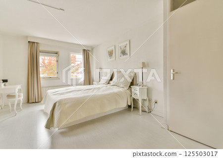 A serene and elegantly designed bedroom featuring soft neutral colors, natural light, and minimalistic decor, perfect for relaxation and comfort. 125503017