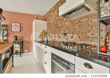Stylish kitchen featuring modern appliances, exposed brick walls, sleek cabinetry, and a cozy atmosphere, perfect for cooking and entertaining. 125503084