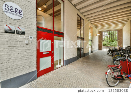A sleek, modern walkway features large windows and ample space for bicycles, creating an inviting urban environment. 125503088
