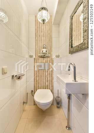 A stylish bathroom featuring modern tiles, a serene Buddha statue, and elegant lighting, creating a tranquil atmosphere for relaxation. 125503149