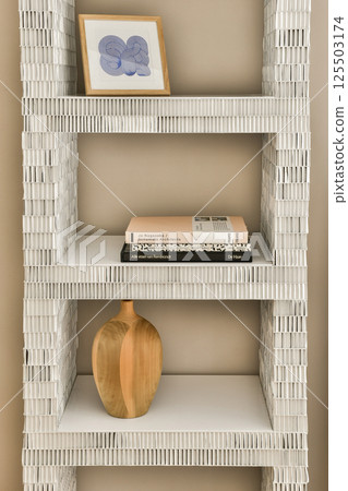 A stylish modern shelving unit made of white material displays a vase and art piece, adding a contemporary touch to any interior space. 125503174