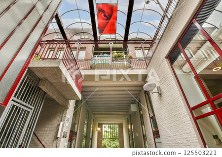 An architectural view featuring a modern building's interior design with a striking glass roof and geometric lines. The bright light enhances the space's ambiance. 125503221