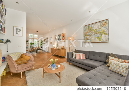 A contemporary living room showcasing a comfortable sofa, stylish furnishings, art pieces, and warm lighting, highlighting cozy interior design elements. 125503248