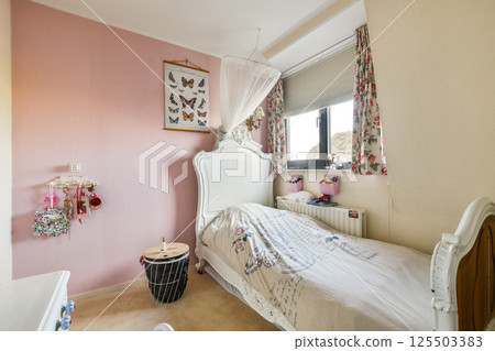 A beautifully decorated bedroom showcasing soft pastel colors, floral curtains, and butterfly art, creating a warm and inviting atmosphere. 125503383