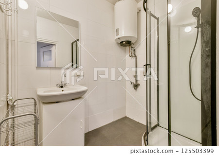 A sleek and modern bathroom featuring clean lines, a compact sink, an elegant shower, and a minimalistic design. Perfect for contemporary living spaces. 125503399
