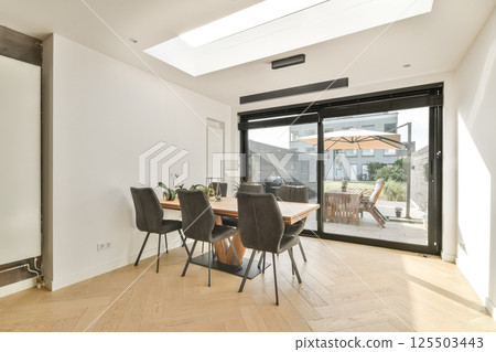 A stylish modern dining room featuring sleek furniture and large windows that open to an outdoor space, enhancing the bright and spacious atmosphere. A stylish modern dining room featuring sleek furniture and large windows that open to an outdoor space, enhancing the bright and spacious atmosphere. 125503443