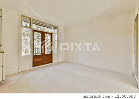 A vacant room featuring large windows that allow natural light to flood in. The minimalist design highlights the spaciousness of the area. A vacant room featuring large windows that allow natural light to flood in. The minimalist design highlights the spaciousness of the area. 125503508