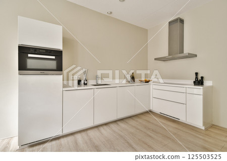 Sleek and contemporary kitchen featuring white cabinets, stainless steel appliances, and a clean layout that enhances functionality and aesthetics. 125503525