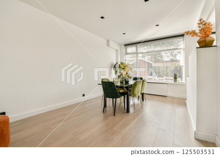 A spacious and bright interior featuring a modern dining setup, highlighting harmony with natural light and clean lines for a minimalist aesthetic. A spacious and bright interior featuring a modern dining setup, highlighting harmony with natural light and clean lines for a minimalist aesthetic. 125503531