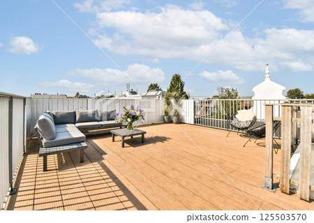 A stylish rooftop terrace featuring a wooden deck, cozy seating areas, and decorative plants, perfect for relaxation and enjoying the view. 125503570
