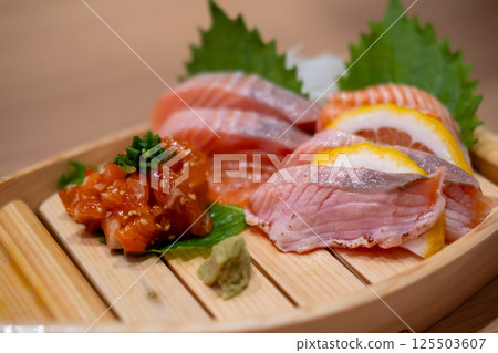 Salmon Sashimi set served on wooden sushi boat, with lemon and wasabi Salmon Sashimi set served on wooden sushi boat, with lemon and wasabi 125503607