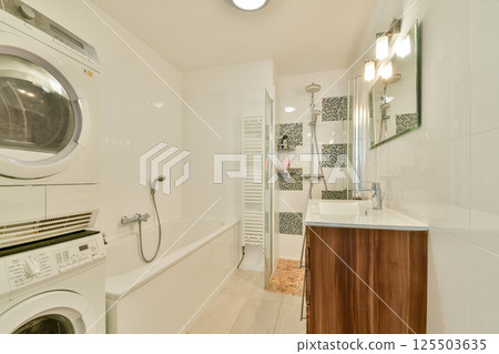 A contemporary bathroom featuring a combination of a washing machine and dryer, a stylish bathtub, and a sleek vanity with modern fixtures. A contemporary bathroom featuring a combination of a washing machine and dryer, a stylish bathtub, and a sleek vanity with modern fixtures. 125503635