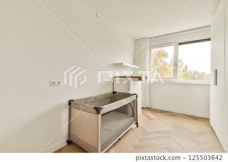 A bright modern nursery features a portable crib and a sleek changing table, accented by natural light filtering through a window. A bright modern nursery features a portable crib and a sleek changing table, accented by natural light filtering through a window. 125503642