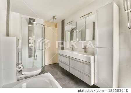 A sleek and modern bathroom design featuring a glass shower, dual sinks, and contemporary fixtures. The clean lines and neutral colors create a calming atmosphere. 125503648