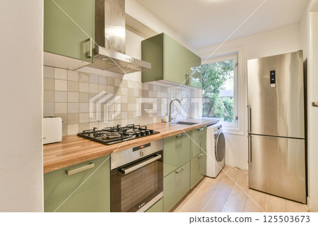 A clean and modern kitchen design featuring sleek cabinets, stainless steel appliances, and natural light streaming through the window. Functional and stylish. 125503673