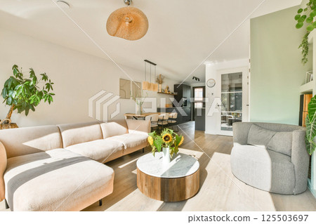 A bright and modern living room featuring a comfortable couch, a decorative coffee table, and vibrant plants. Sunlight streams in, creating a warm atmosphere. A bright and modern living room featuring a comfortable couch, a decorative coffee table, and vibrant plants. Sunlight streams in, creating a warm atmosphere. 125503697