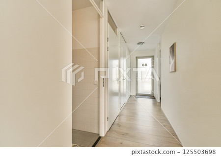 A sleek and contemporary hallway featuring light colors, wooden flooring, and minimalist design elements, creating a spacious and inviting atmosphere. A sleek and contemporary hallway featuring light colors, wooden flooring, and minimalist design elements, creating a spacious and inviting atmosphere. 125503698